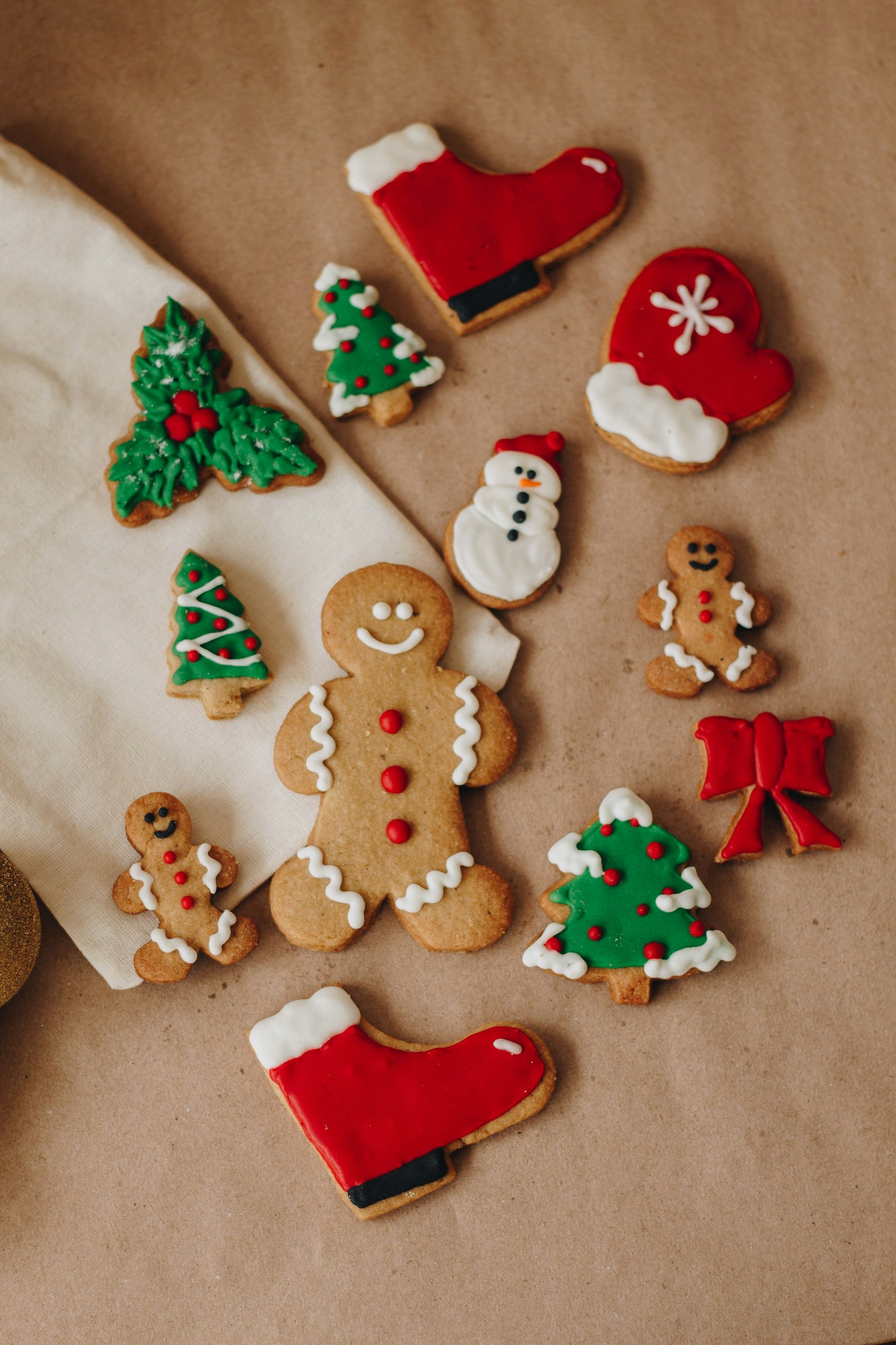 Iced gingerbread cookies shaped as trees, gingerbread people, stockings and snowmen on baking paper